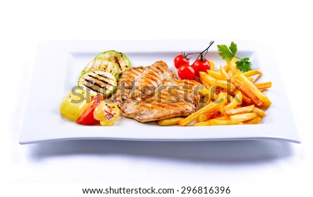Tasty grilled chicken with french fries and vegetables on a white plate