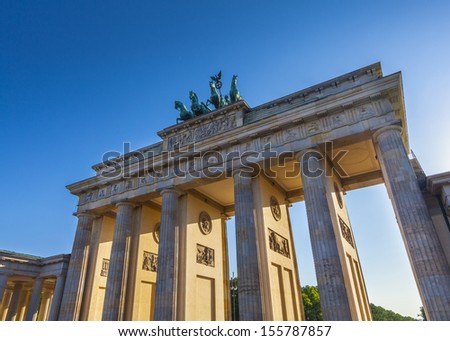 Sunlight illuminating Brandenburg Gate (1788) inspired by Greek architecture, built as a symbol of peace and nationalism, now an emblem of reunification.
