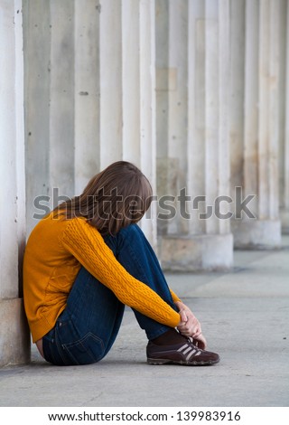 Sad girl sitting near columns
