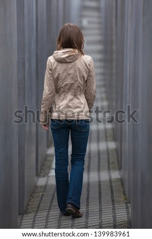 Girl walking away through grey corridor