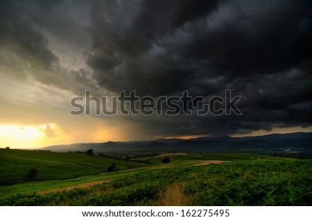 A bank of angry storm clouds on sunset\'s light