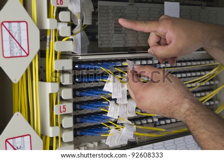 While one hand is holding a label on the fiberoptic cable the other one is checking labels.