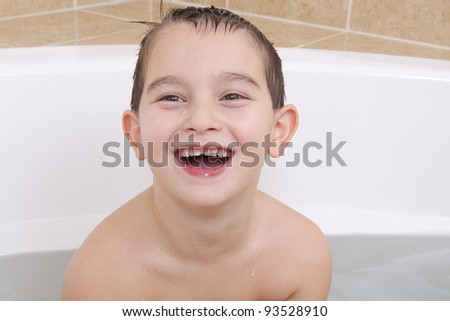 Happy kid is smiling in the bathtub while his hair wet.