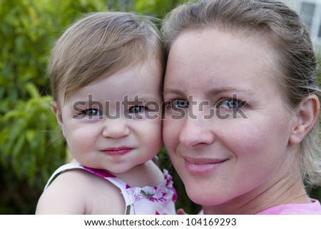Mother and Daughter headshot. Mother looking at camera with a secure, trusting feelings. Similar impression on 11 months baby.