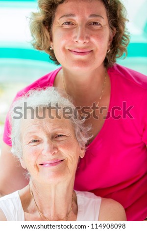 Old mother and her daughter posing with satisfied look.