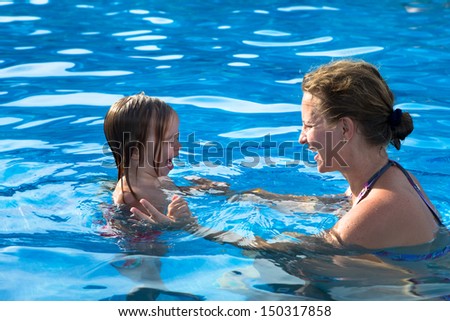 Mother teaching her daughter how to swim by how not to scare of water