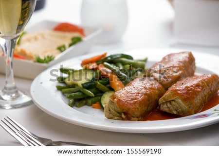 Turkish stuffed cabbage rolls served along with steamed green beans, carrots and zucchini, complemented with hummus plate and white wine.