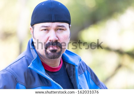 Man with a goatee looking determined attitude on a green sunny background
