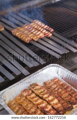 Cooking Adana kebabs on the restaurant style grill, smoke  coming out from them that they might be ready