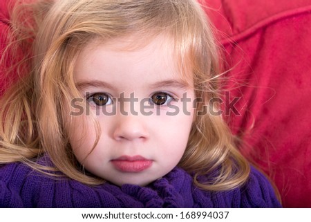Close up facial portrait of a beautiful innocent young blond girl with a solemn wide eyed expression staring into the camera