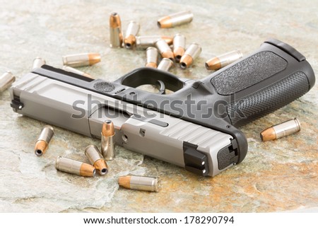 Handgun surrounded with scattered bullets littering the top of an old grungy wooden surface depicting crime, terrorism and violence or protection of personal assets
