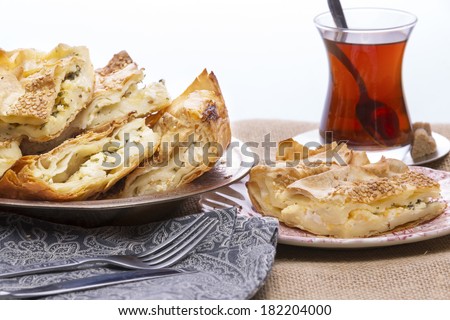 Turkish borek served at a party with cut portions heaped on a plate showing the crispy flaky texture of the yufka,or phyllo, pastry