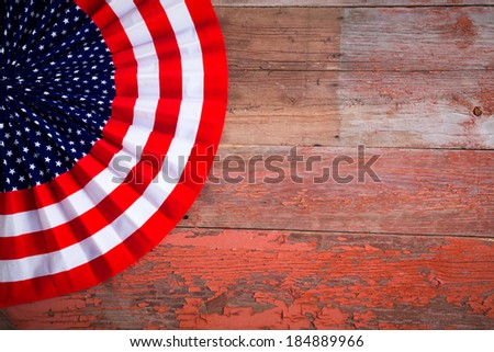 Patriotic Independence Day Badge to celebrate the Fourth of July in the colors of the American flag with stars and stripes on a rustic wooden table with copyspace