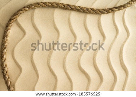 Nautical background of wavy golden beach sand with a ripple effect with a decorative curving rope border and copy space