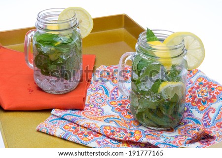 Refreshing chilled drinks lemon and mint in iced water served in glass jars garnished with lemon
