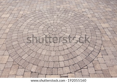 Architectural background of an ornamental pattern in outdoor patio paving with bricks arranged in a circular pattern of concentric geometric circles