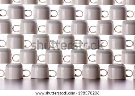 Abstract background pattern of drying coffee cups neatly stacked in rows on top of one another with the handles in each alternating row facing the opposite direction