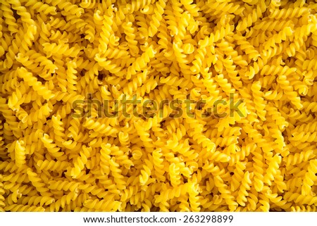 Full frame food background of colorful yellow spiral gluten-free corn and rice fusilli pasta used as an ingredient in Mediterranean cuisine for people with a gluten allergy