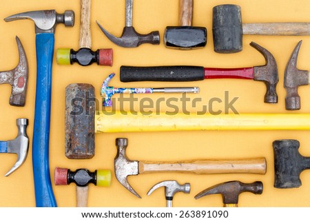Display of a diversity of hammers in a tool kit for DIY, carpentry, construction, mallets and a sledgehammer in a neat arrangement on a wooden table, overhead view