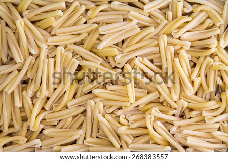 Background texture of dried Italian casarecce, a tubular regional pasta from the island of Sicily made from durum wheat dough used in maccaroni dishes