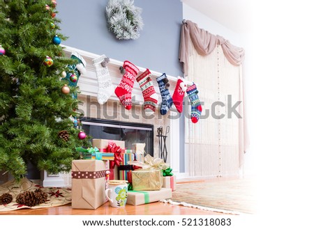 Pile of Christmas gifts under the tree with colorful stockings hanging on the mantelpiece and a high key bright copy space to the side for your holiday message