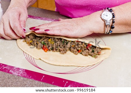Experienced Hands are wrapping Turkish traditional food Pide with seasoned ground beef.