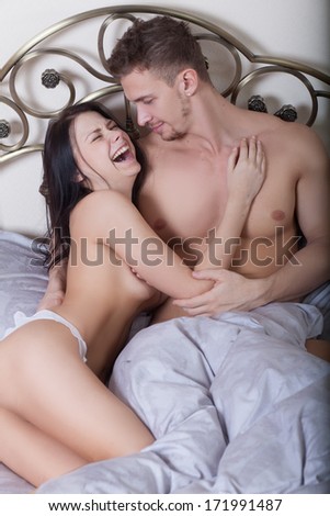 Close up of a sexy couple kissing and playing in bed. sex toys.