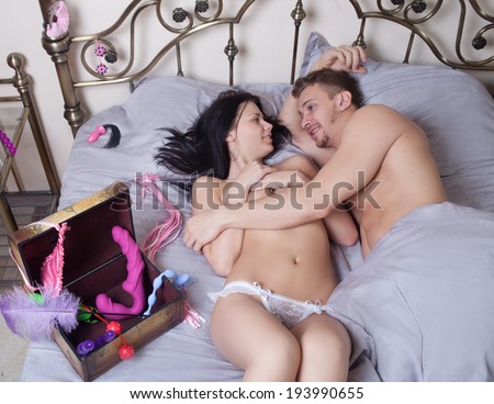 sexy couple lying in bed. use sex toys.