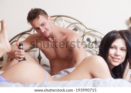 sexy couple lying in bed. use sex toys. drinking wine