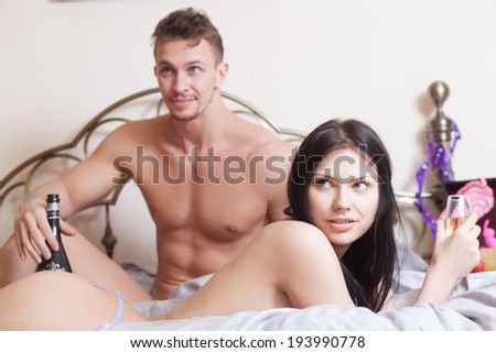 sexy couple lying in bed. use sex toys. drinking wine