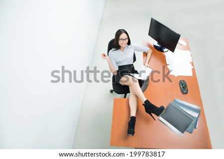 beautiful business woman holding a paper. feet on the table. smiling