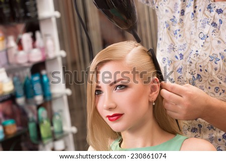 hairstylist makes hairstyle for beautiful girl