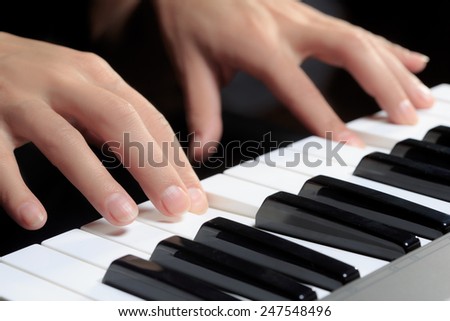 Girl's hands on the keyboard of the piano