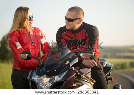 biker man and woman sitting on a motorcycle.