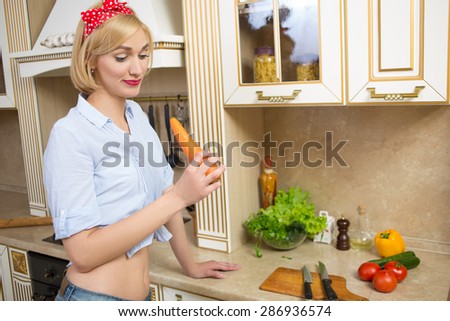 girl holding a big carrot in the kitchen