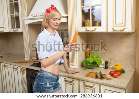 girl holding a big carrot in the kitchen