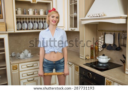 woman in apron with rolling pin in hand in the kitchen.