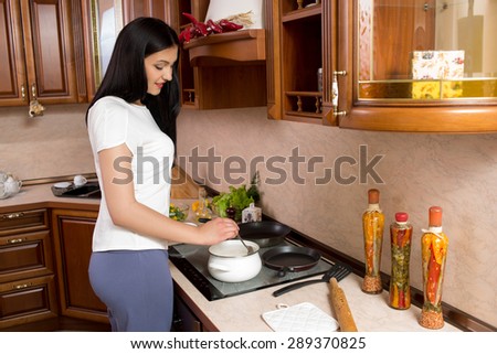 Kitchen Woman. Young beautiful girl holding a frying pan.  Kitchen background