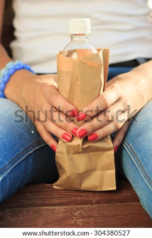 girl holding a plastic bottle in a paper bag