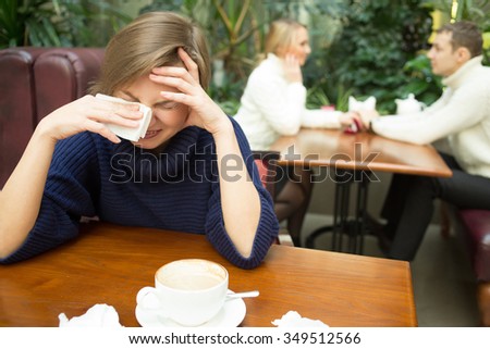 girl crying on background happy couple. sitting in cafe