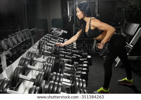 sexy woman doing workout with dumbbells  in gym. exercise for the back and triceps