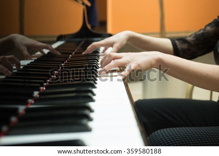 Women\'s hands on the keyboard of piano. girl plays music