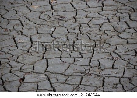 Global warming concept of arid cracked ground - dry gray mud background texture