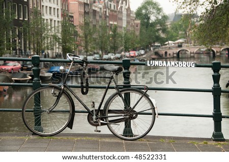 Black bike parked on Lijnbaansbrug bridge on one of the Amsterdam canals in the Netherlands
