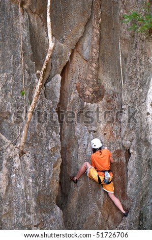 female alpinist climbing a rock