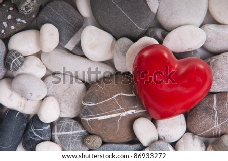 Red heart among river pebble stones
