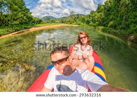 Young couple making a selfie shot while canoeing in Kao Sok rainforest river