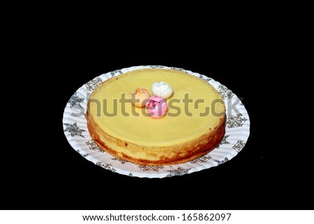 Pie with cream of yellow color with confectionery ornament on a paper plate