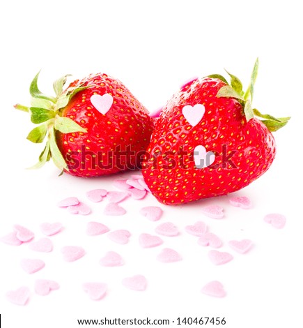 Funny ripe strawberry isolated on white background, decorated with sweet hearts, closeup