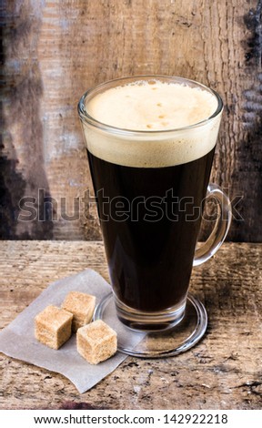Hot coffee in a Latte Glass and sugar on Old wooden table or grunge wood background